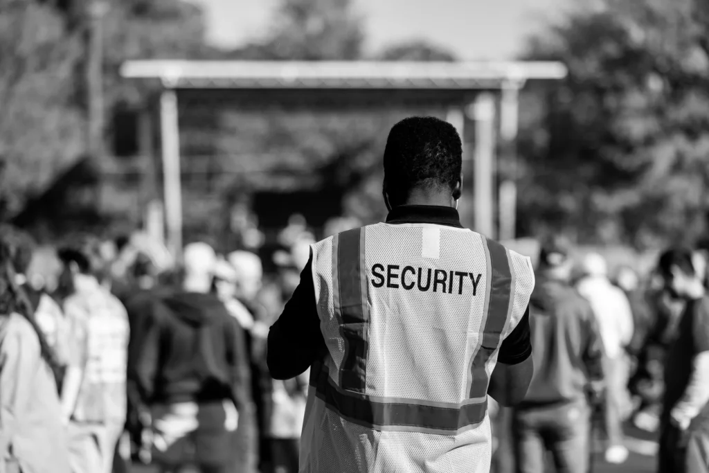 Security officer in a high-visibility vest watching over an outdoor event crowd