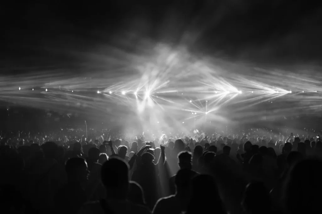Crowd at a night concert under stage light beams