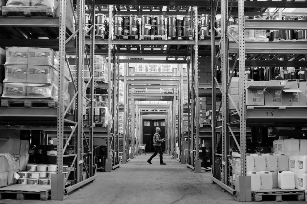 Worker walking between tall shelves in a distribution warehouse